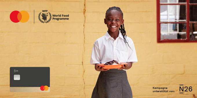 Ein lächelndes kleines Mädchen mit einem Teller mit Essen in der Hand.