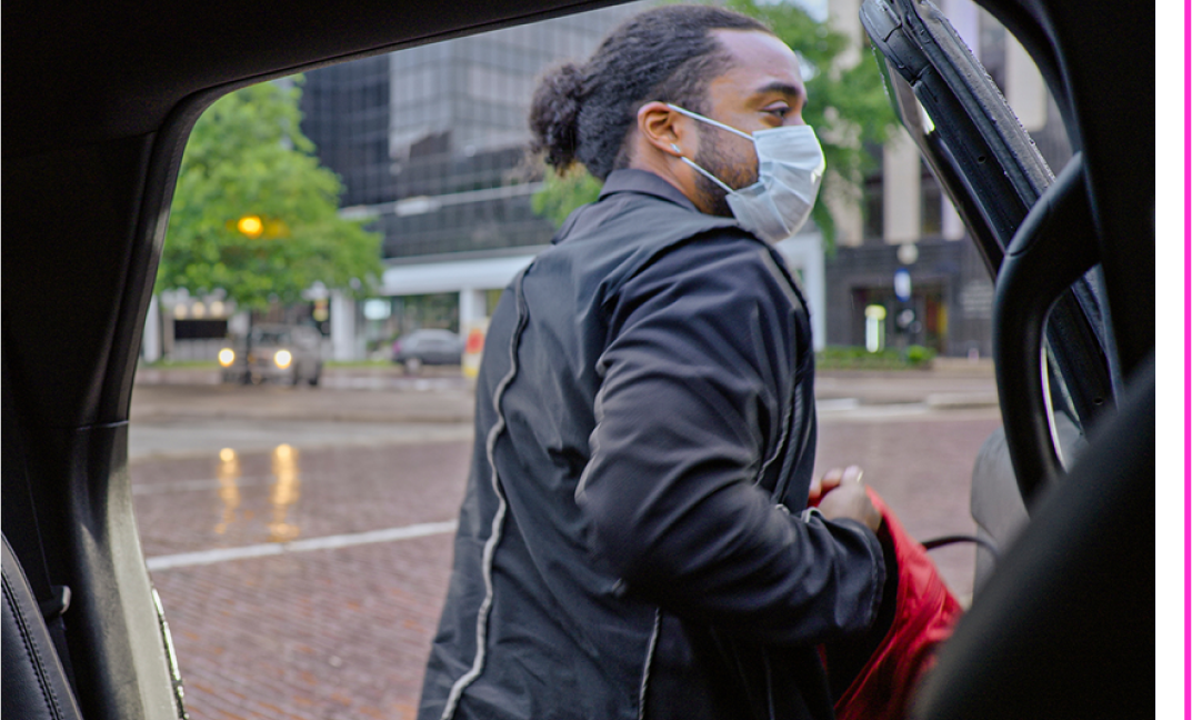 Lyft rider getting out of the back seat wearing a mask.