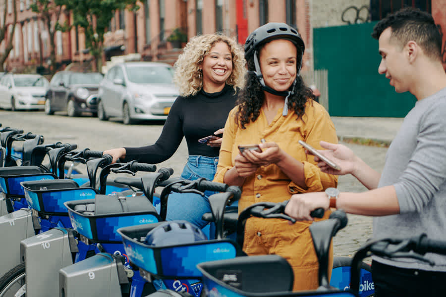 group of people standing near a dock of CITI Bikes.