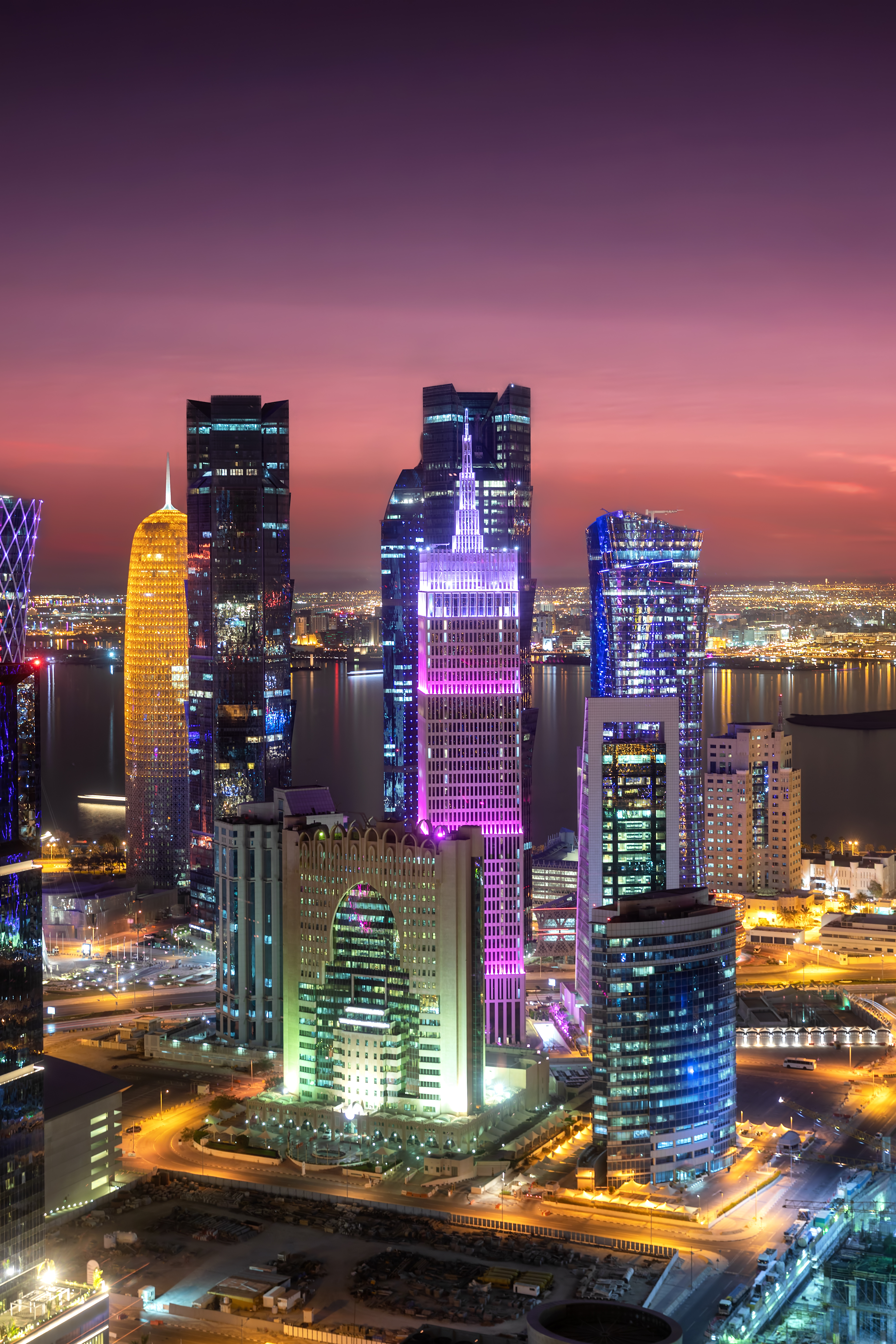 The illuminated, modern city centre of Doha in the State of Qatar during night time - portrait