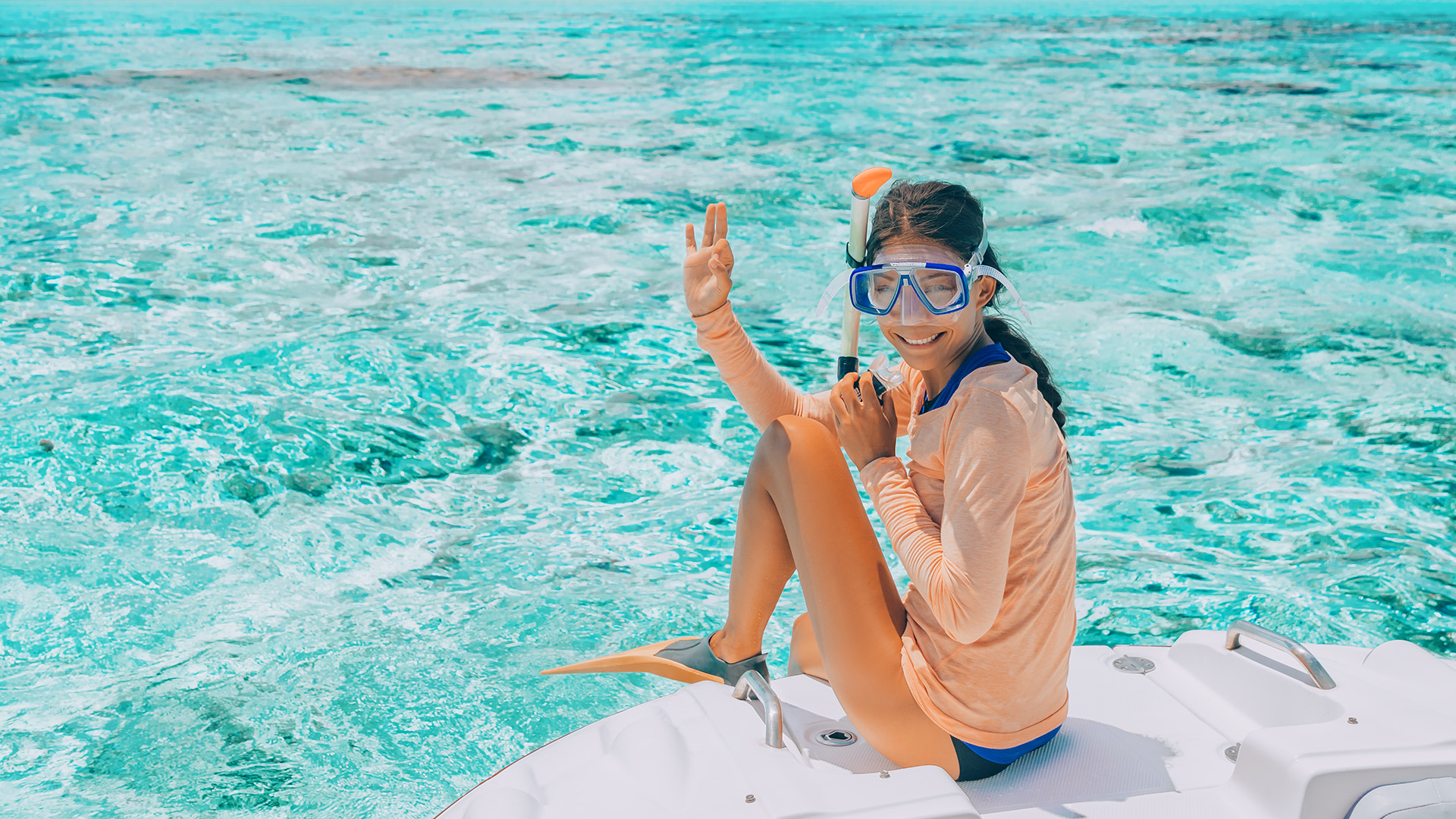 Woman going snorkeling in pefect clear water at coral reef.