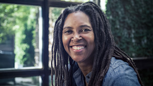 Close-up of a woman with dreadlocks smiling.