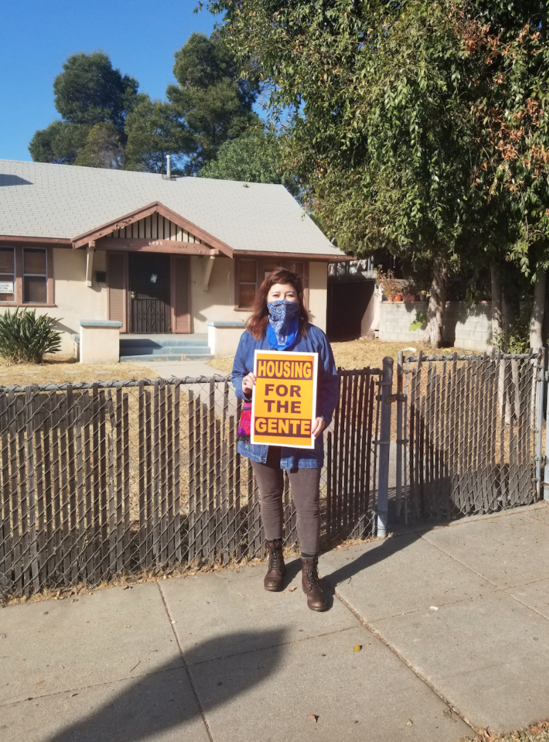 Screen Shot 2020-12-22 at 11.59.30 AM Iris De Anda stands outside of one of the state-owned homes that is boarded up and unoccupied in the El Sereno neighborhood of Los Angeles.