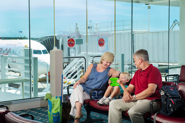 A family at a gate waiting for there plane to arrive.