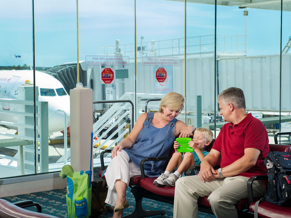 A family at a gate waiting for there plane to arrive.