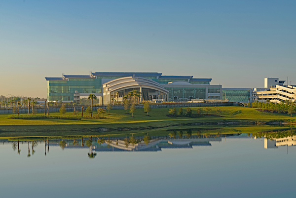 Outside looking at the front of Terminal C. A lake is in the foreground. Terminal C in background with blue skies.