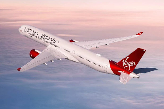 Virgin Atlantic airline fly's over clouds with a pink sunset in the background.