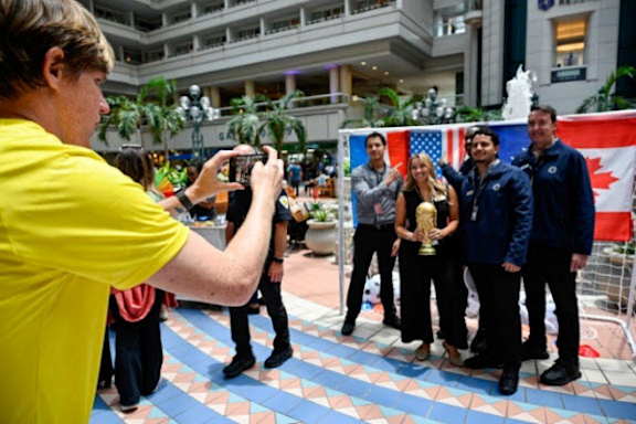 Group photo of guests and airport employees who stopped to spin the MCO prize wheel for a chance to win branded swag and travel accessories.