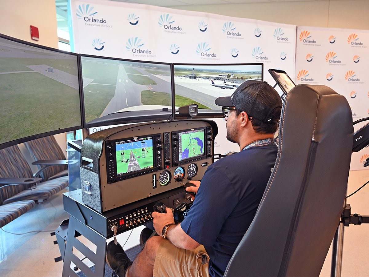 A man with a baseball cap sitting in front of a flight simulator.