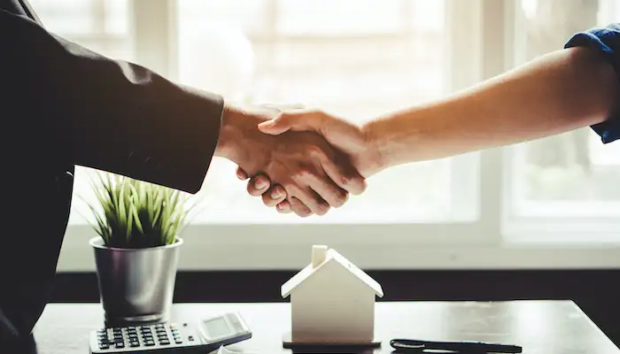 two people shaking hands over a desk