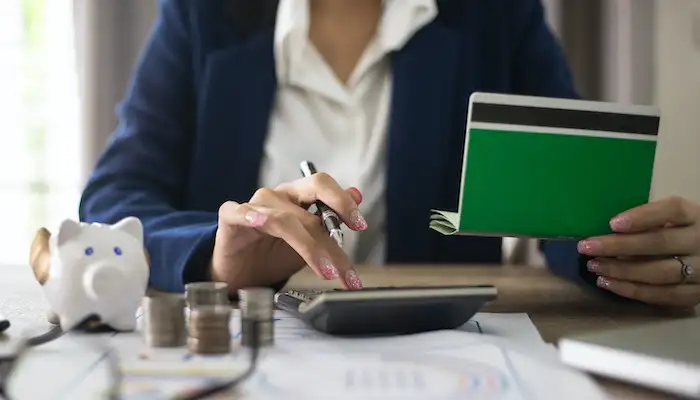 woman sat at desk using a calculator to manage finances