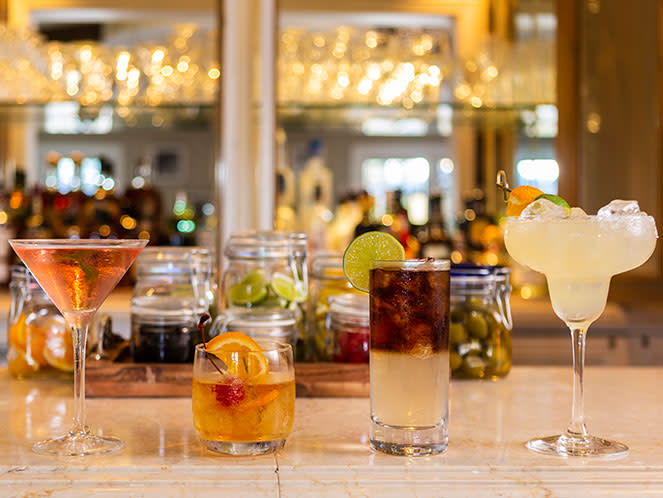 A variety of cocktails displayed on a bar.