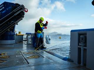 Fish farmer submerging drone from boat
