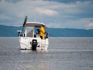Fisherman fishing from back of boat
