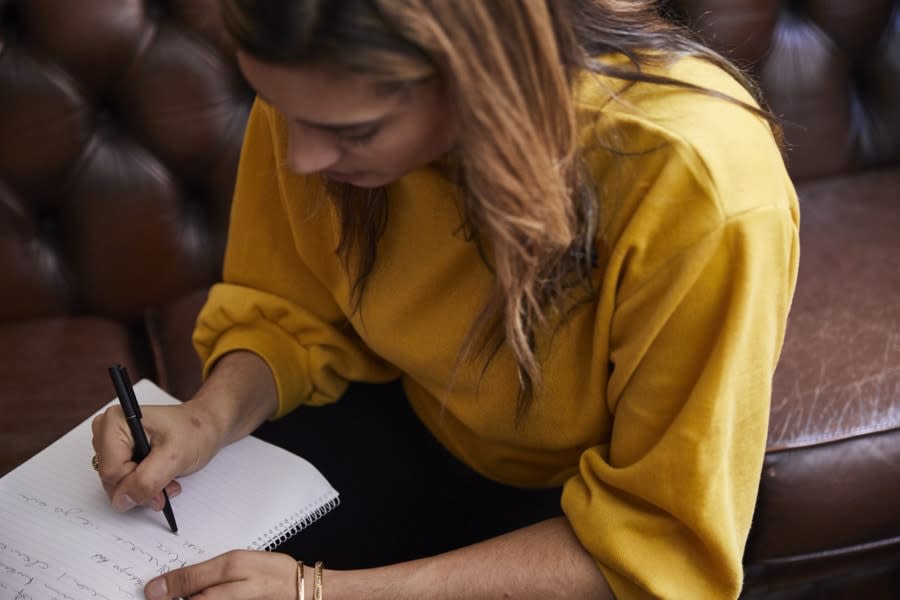 Girl in yellow sweater writing down notes
