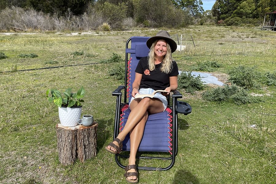 woman lounging in chair reading in grass field