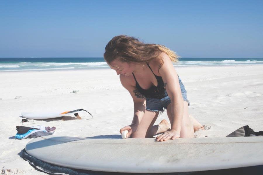 Girl waxing surfboard