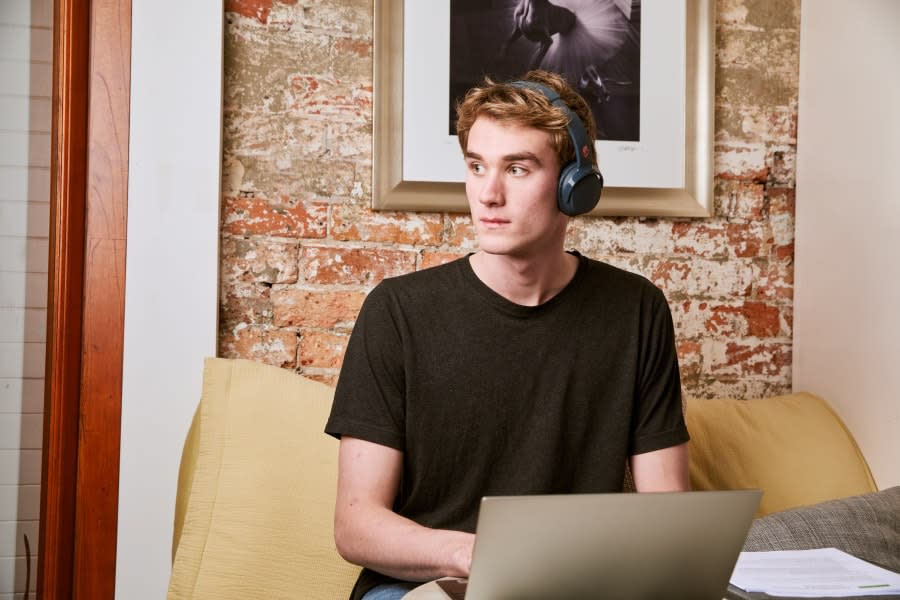 young person in a black shirt with headphones on using their laptop