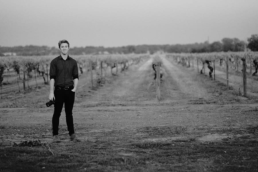 Videographer Harrison Slattery standing in front of a vineyard after taking photographs at a local wedding in Albury