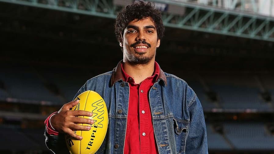 Image of Tony Armstrong holding an AFL ball and smiling at the camera.