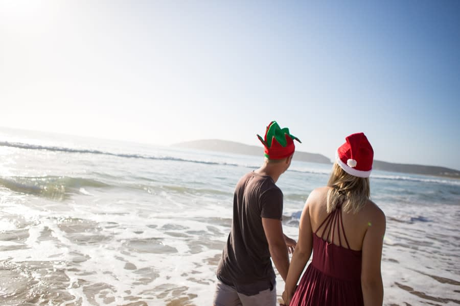 Boy and girl on beach with christmas hats