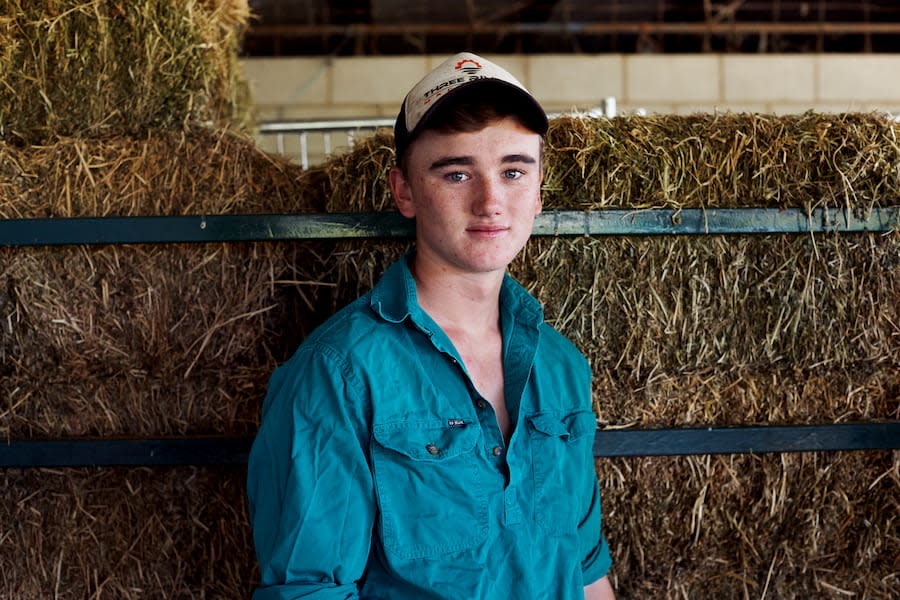 Image of a teen body standing in a barn. He is looking at the camera and smiling.