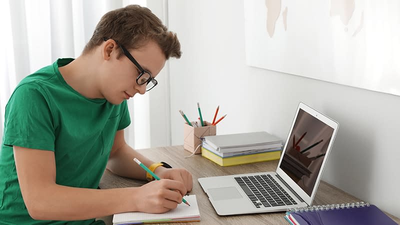 Teenage boy in green shirt studying at desk 2