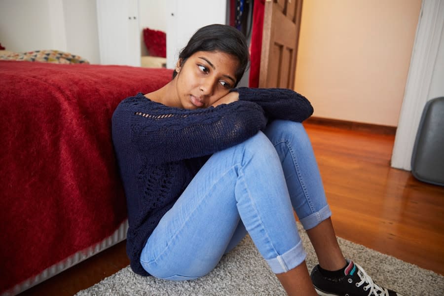 girl in jeans sitting down looking sad
