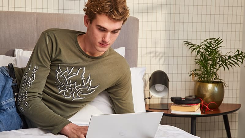 teenage boy using laptop on bed