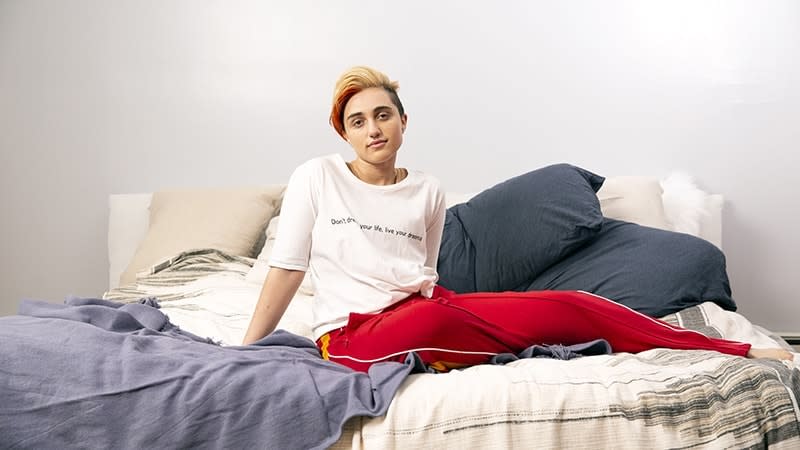 a transmasculine gendernonconforming person sitting on a bed