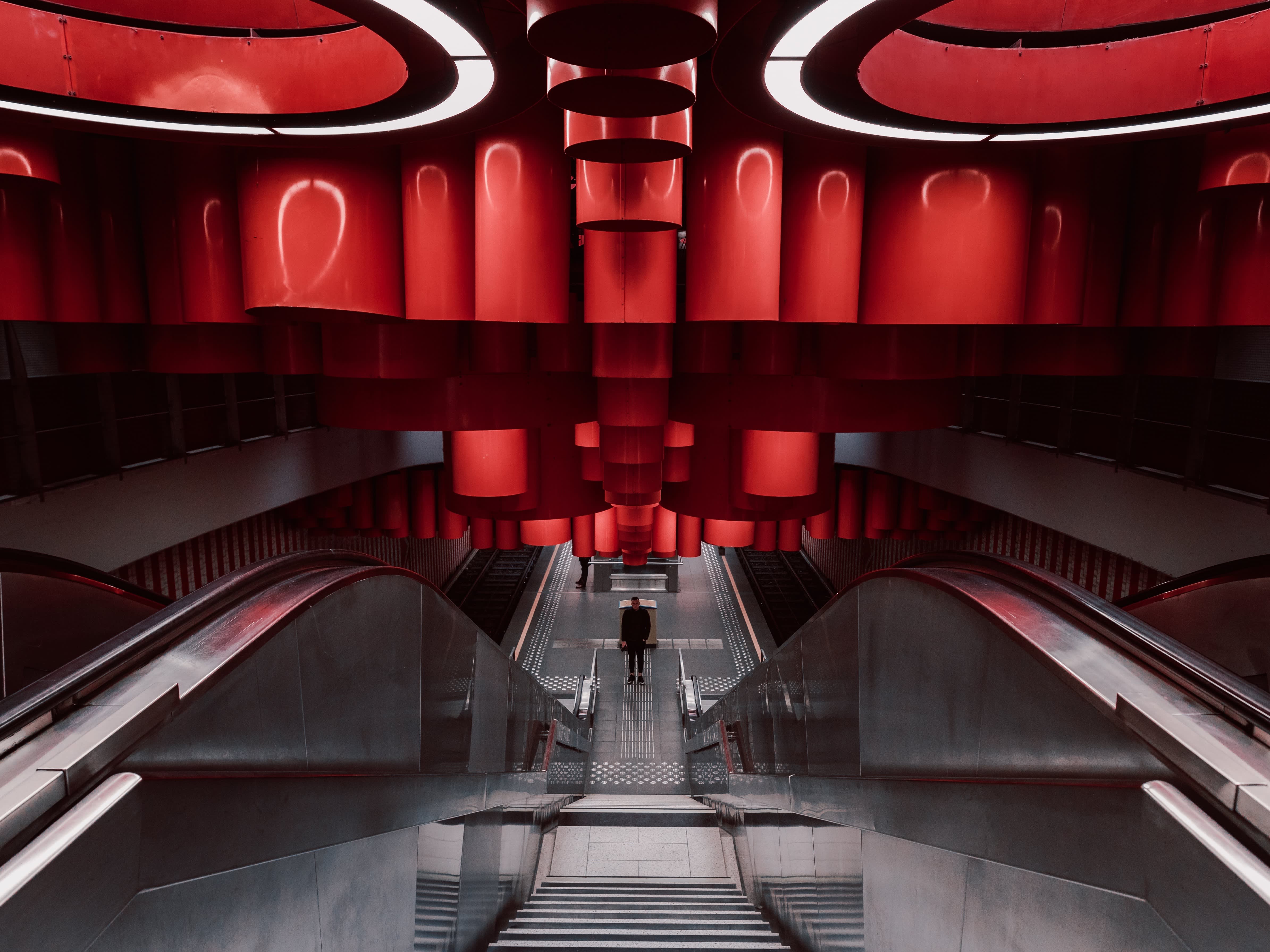 futuristic ceiling with red tubes and shapes above escalator