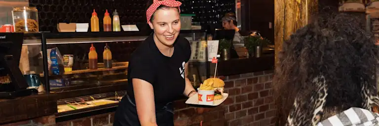 Grill'd staff member delivering a burger at a City Support Dinner