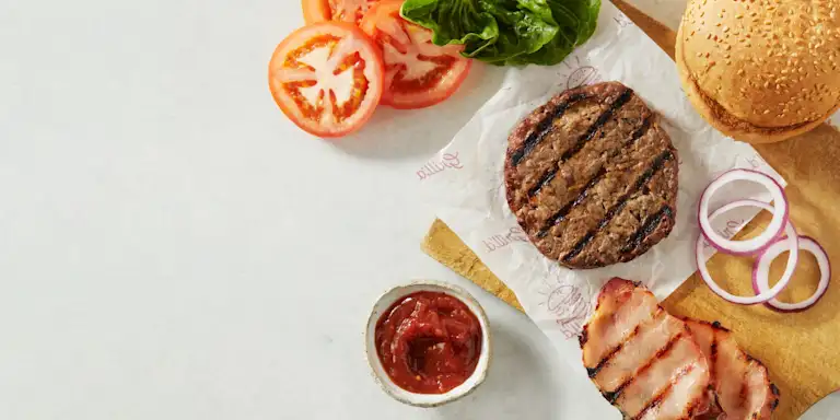 Sliced tomatoes, beef pattie and bacon slices on a background