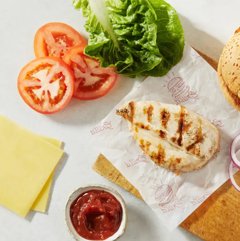 Spread of grilled chicken breast, bacon, tasty cheese, sliced tomato and lettuce
