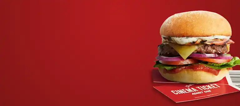 A crispy bacon and cheese beef burger placed on top of cinema ticket vouchers.