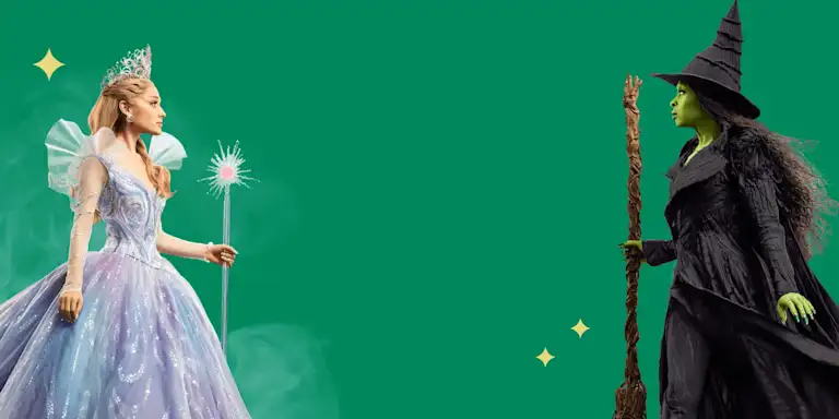 Glinda and Elphaba posed looking at each other. Glinda holds her scepter, and Elphaba holds her broomstick.