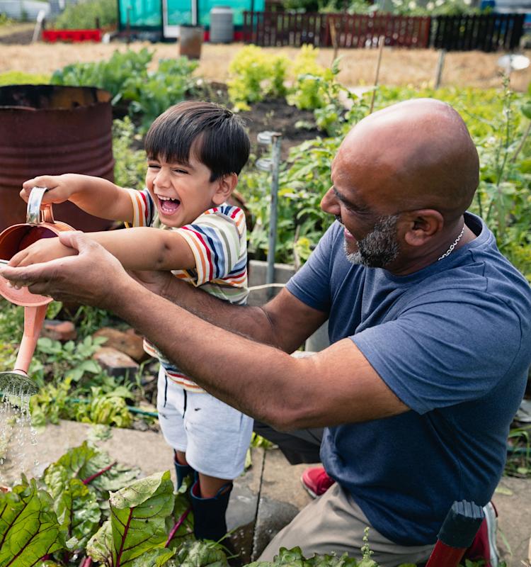 grandfather and grandson in the garden with a watering can