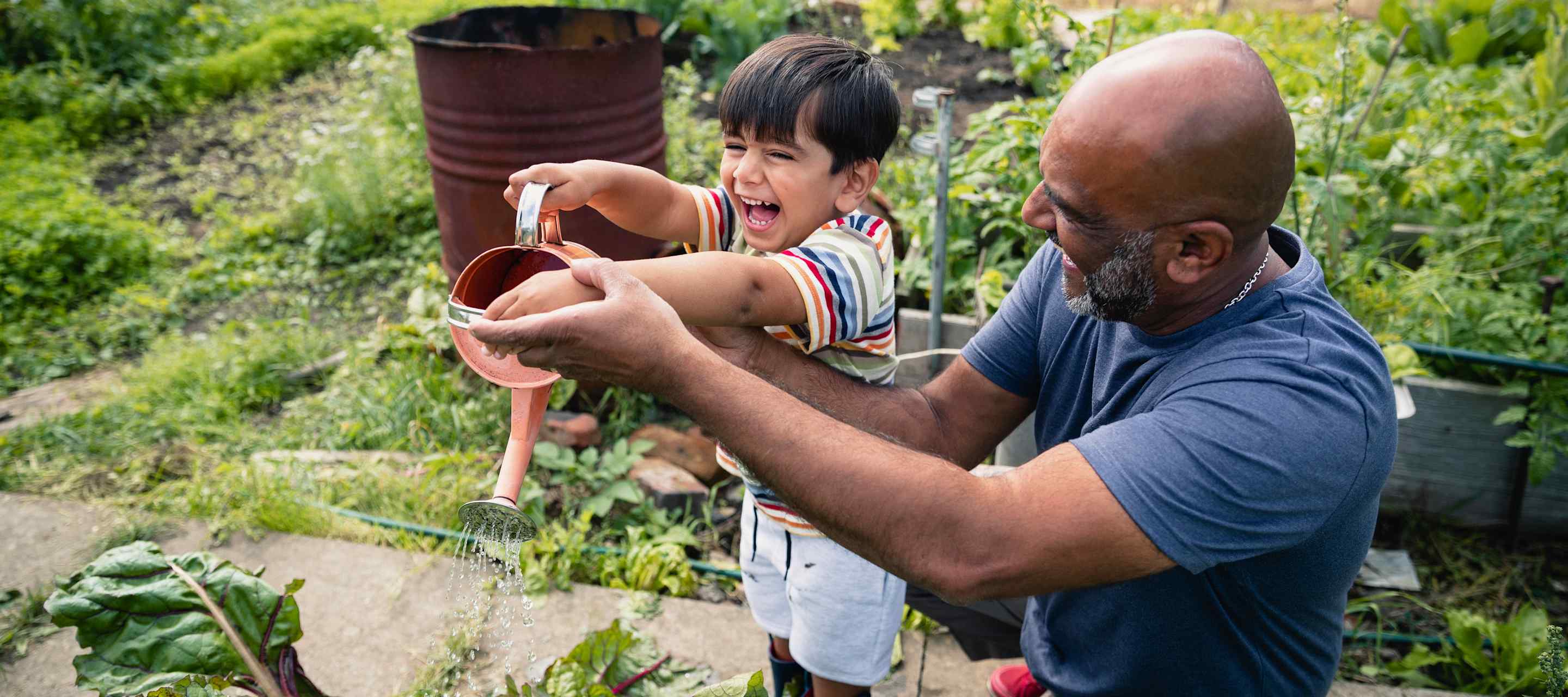 grandfather and grandson in the garden with a watering can