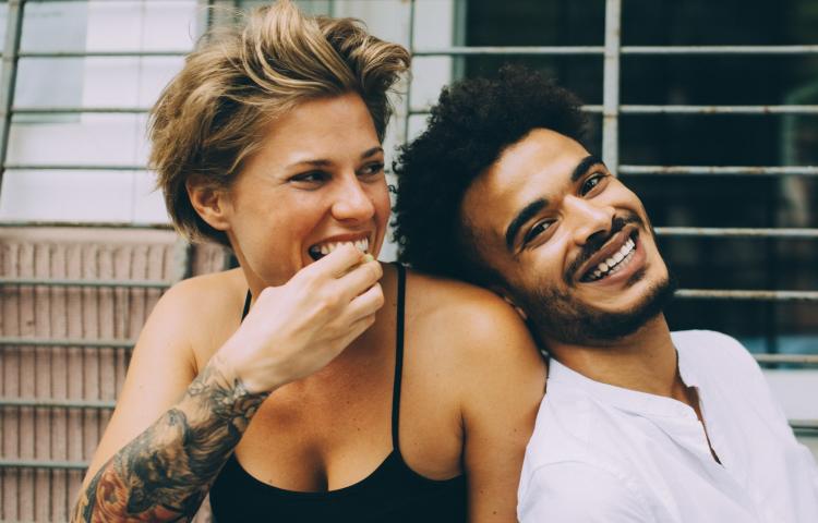 Woman eating whilst man laughs