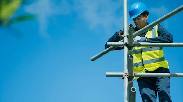 Builder assembling scaffolding high up