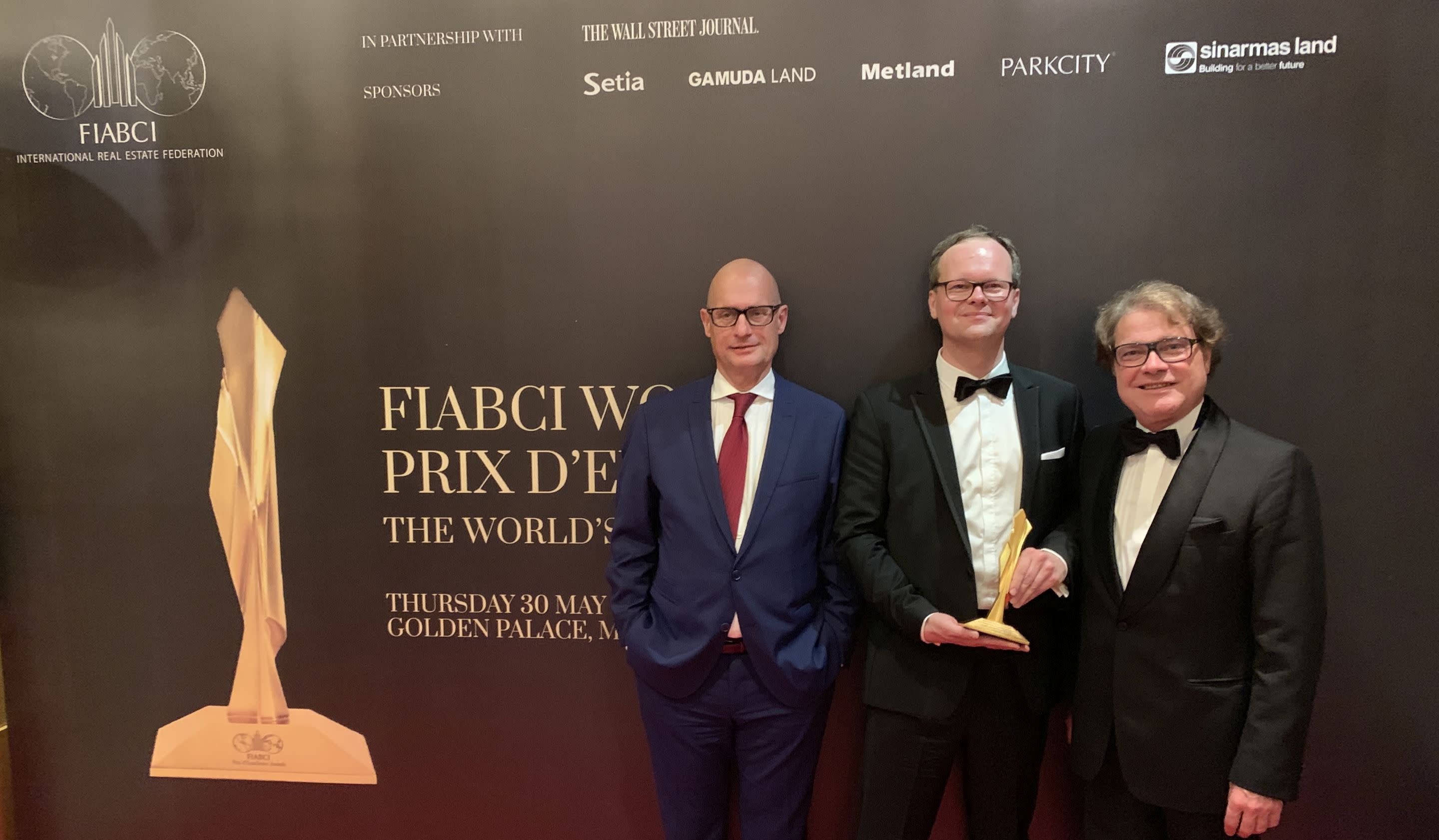 Bild: Drei Herren in Anzügen mit dem goldenen Award