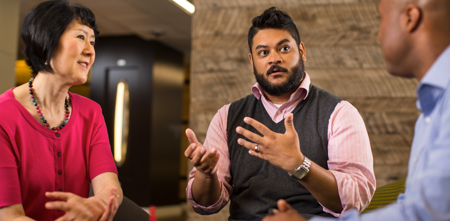 Three people having an engaging discussion whilst sitting around a table.