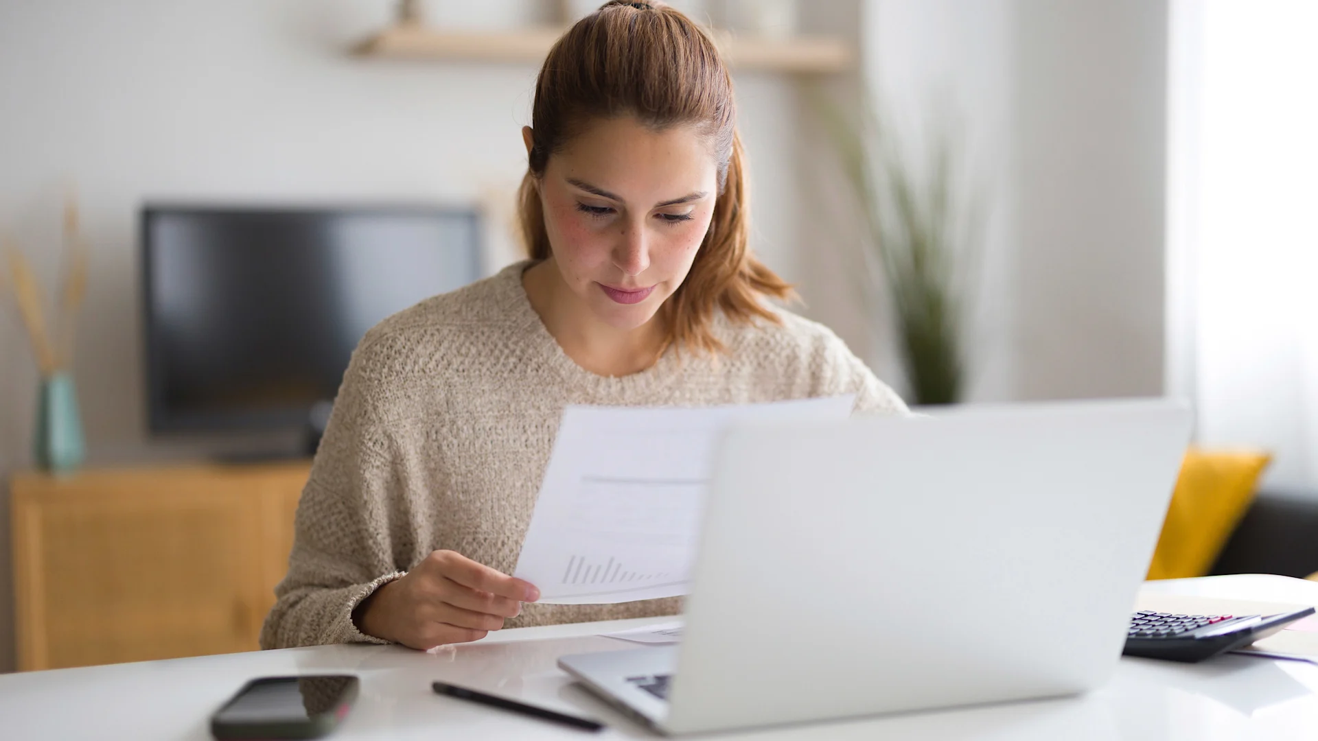 Reducing your tax liability Young woman calculating domestic bills, checking graphs and invoices while working from home.