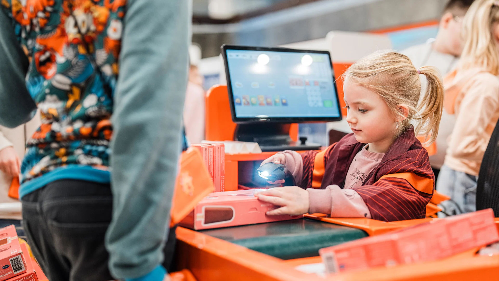 Uno sguardo nella Mini Migros Una ragazza è seduta alla cassa e sta scansionando prodotti