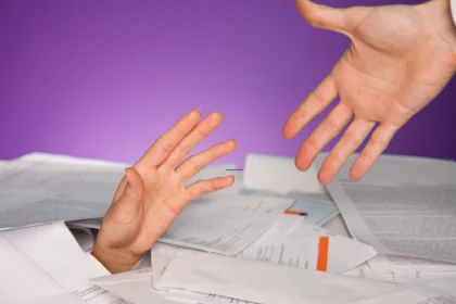 Financial help concept, photo of a hand reaching up from a pile of papers
