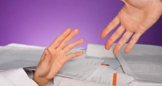 Financial help concept, photo of a hand reaching up from a pile of papers