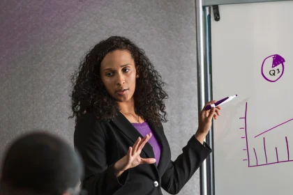 businesswoman drawing on whiteboard and presenting to colleagues 