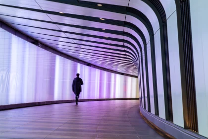 Businessman walking along the illuminated lightwall corridor, connecting One Pancras Square with King's Cross underground station in London