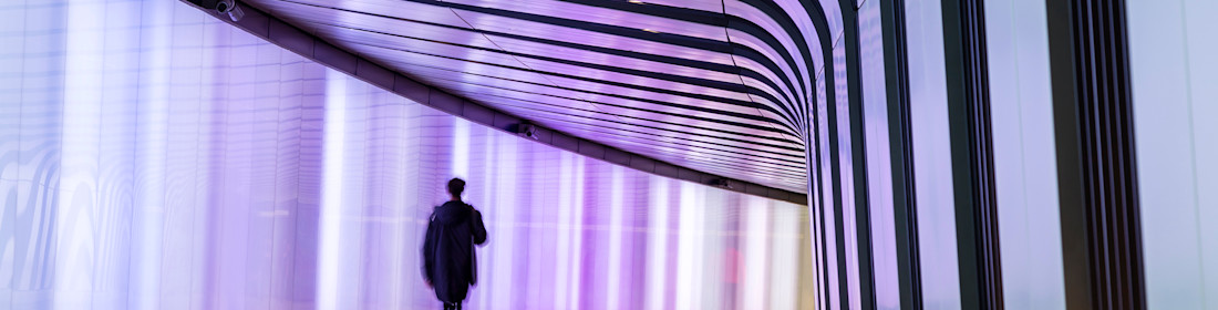 Businessman walking along the illuminated lightwall corridor, connecting One Pancras Square with King's Cross underground station in London