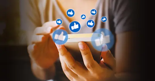 Person using mobile device with "like" icons floating out from the screen